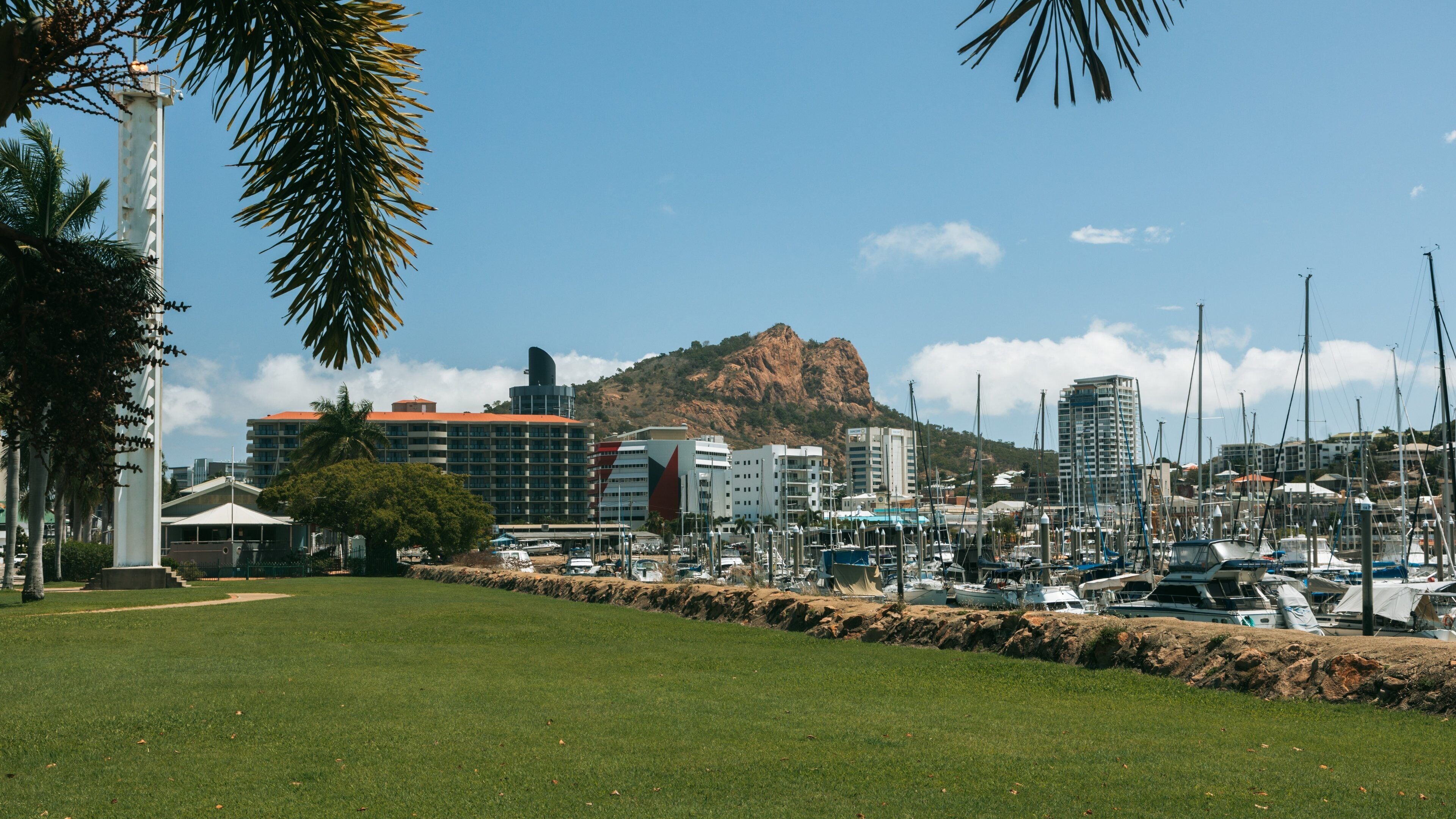 A marina with boats, a mountain in the background, and buildings.