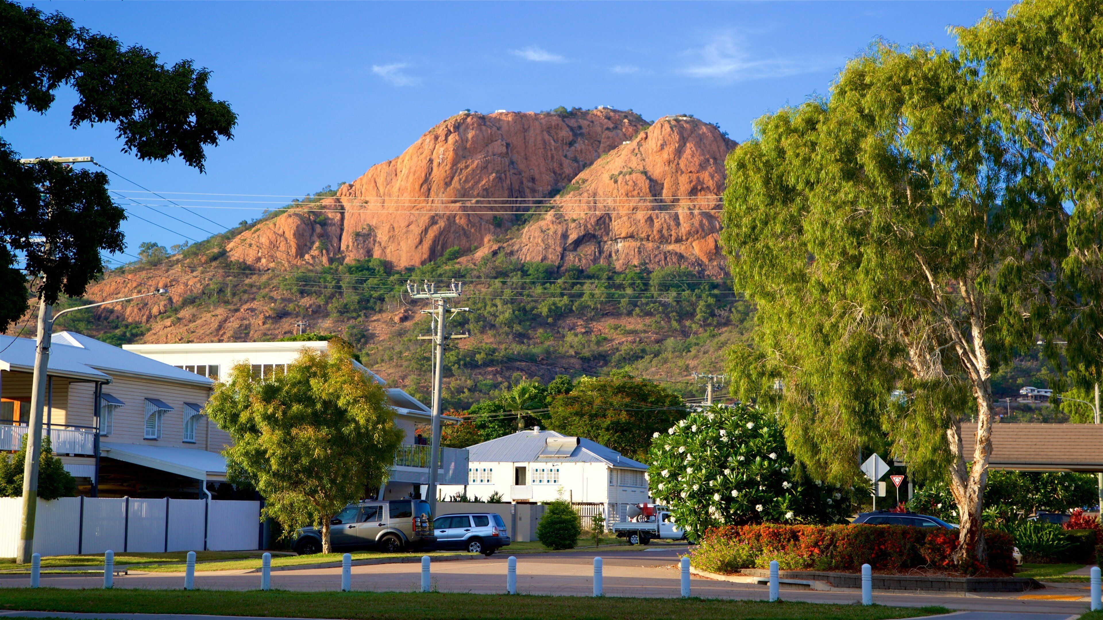 A residential area with houses, a mountain, and a clear sky.