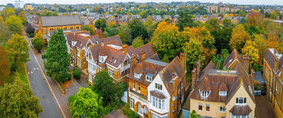 A residential area with terraced houses, a church, and a mix of trees with autumn foliage.