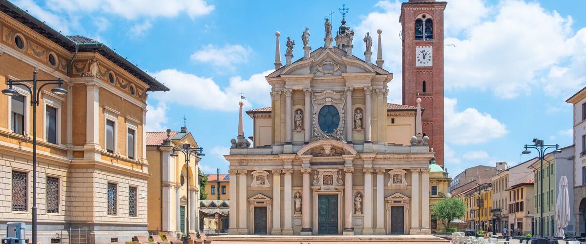 A historic plaza with a prominent church featuring a clock tower and statues.