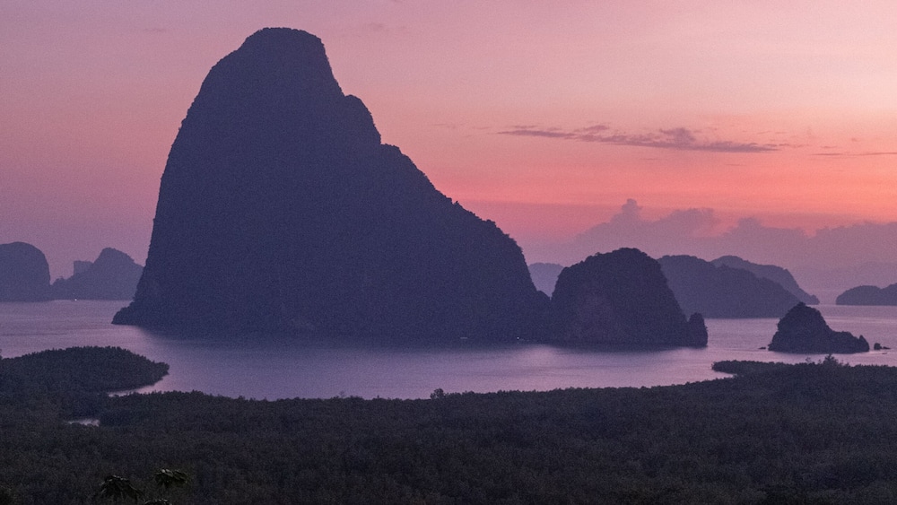 couple watching sunrise over the bay of Phangnga Thailand, men and woman at Samet Nang She viewpoint during sunrise Thailand
