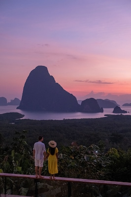 couple watching sunrise over the bay of Phangnga Thailand, men and woman at Samet Nang She viewpoint during sunrise Thailand