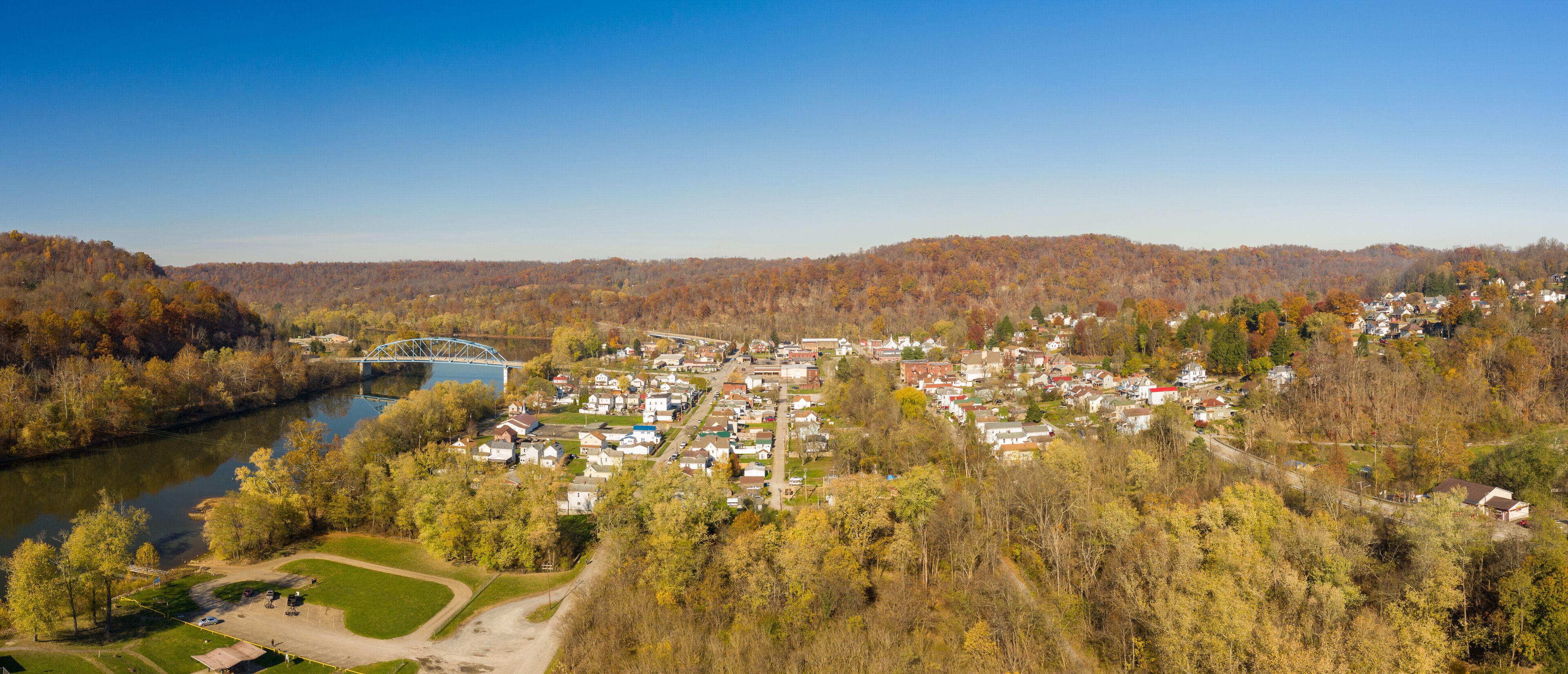 A river, a bridge, and a town surrounded by autumn foliage.