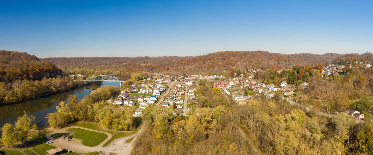 A river, a bridge, and a town surrounded by autumn foliage.