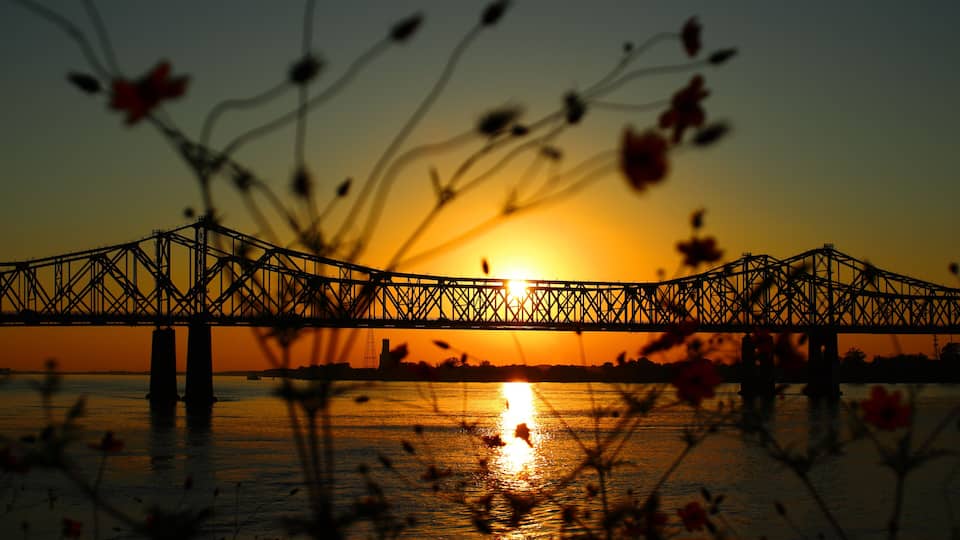 A bridge at sunset with the sun reflecting on the water.
