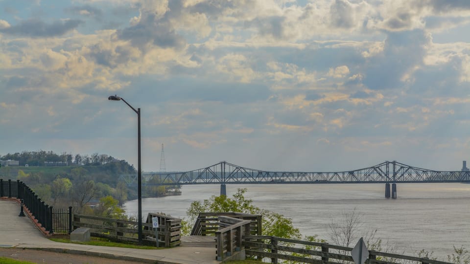 A river with a bridge, a wooden walkway, and a street lamp.
