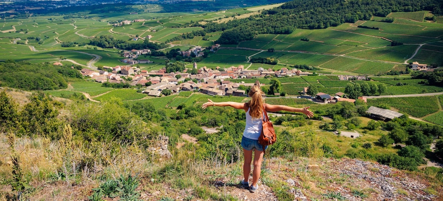 Woman with open arms admiring green vineyard in Beaujolais region, France