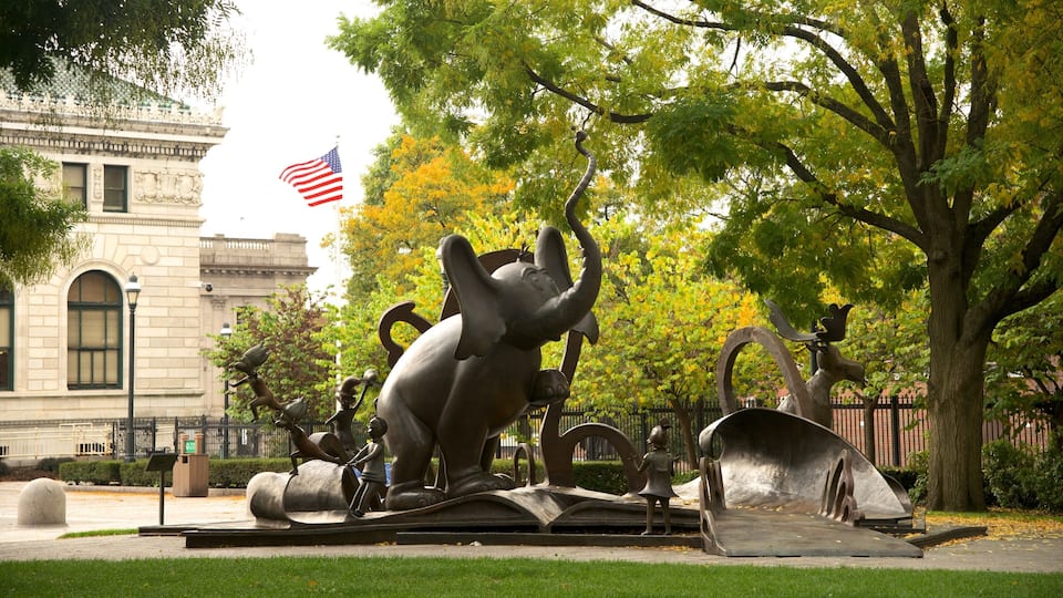 A sculpture garden with a large elephant sculpture, a flag, and trees.