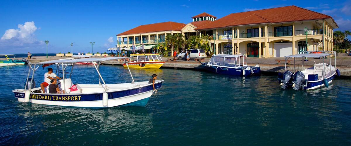 A marina with several boats docked, a building with a red roof, and a clear blue sky.