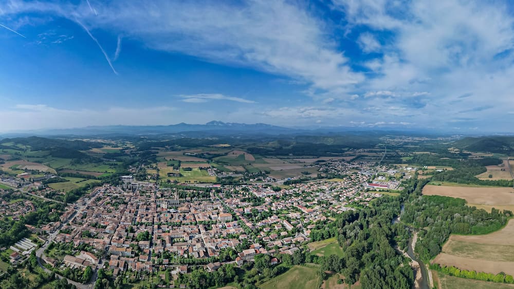 Une vue aérienne d’une ville entourée de champs et de montagnes.