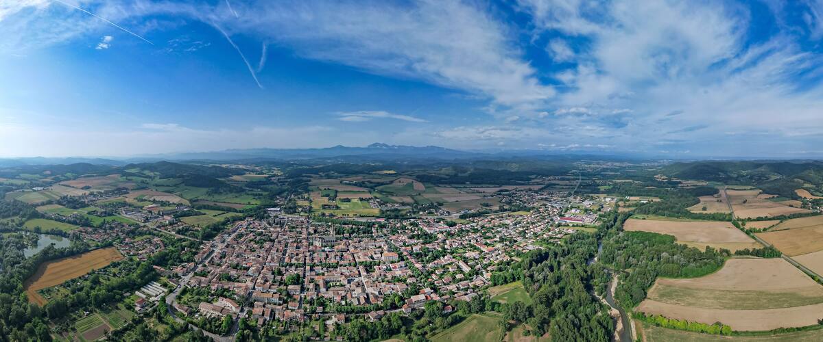 An aerial view of a town surrounded by fields and mountains.