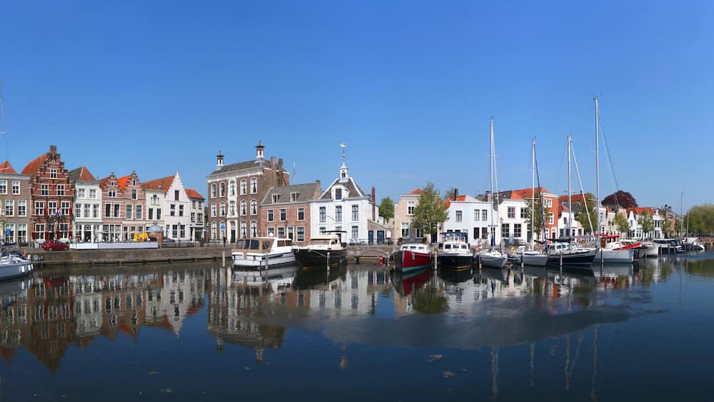 A canal with boats, historic buildings, and a clear blue sky.