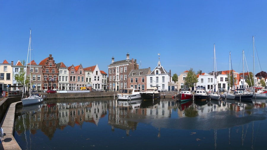 Panoramic view of the historical harbor in the old town of Goes / Netherlands with ancient house facades, motor boats and sailing yachts