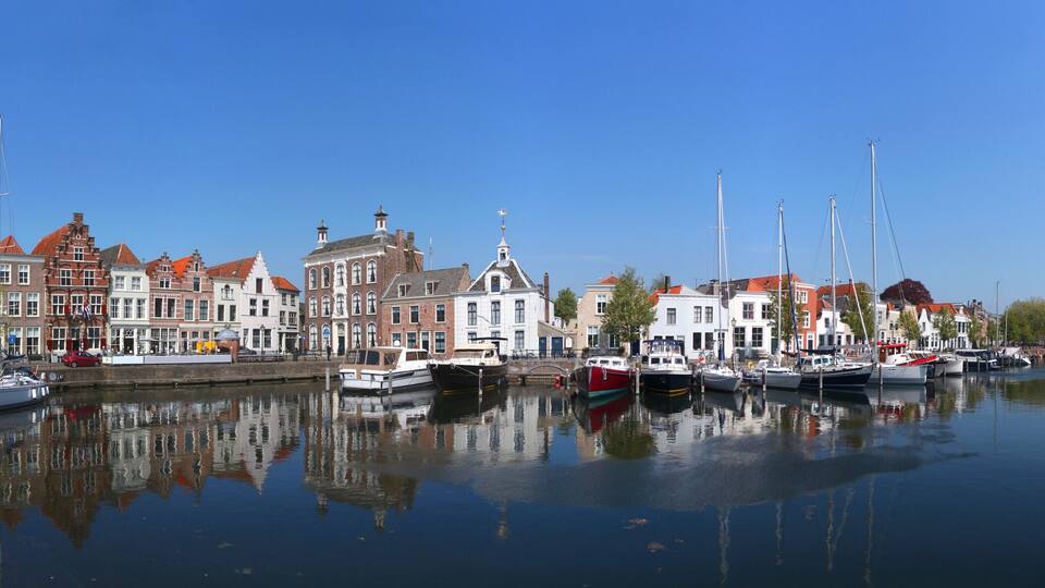 A canal with boats, historic buildings, and a clear blue sky.