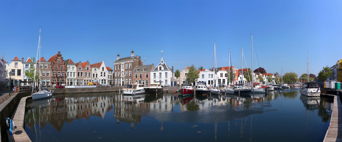 A canal with boats, historic buildings, and a clear blue sky.