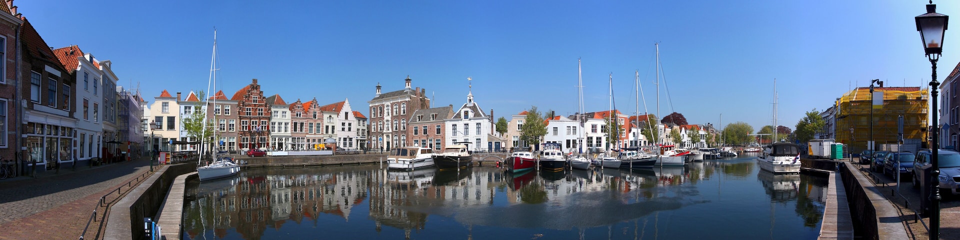A canal with boats, historic buildings, and a clear blue sky.