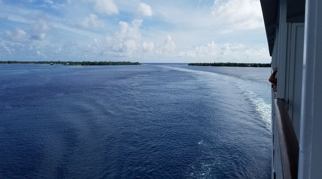 The cruise ship M/S Paul Gauguin is one of few cruise lines to visit Rangiroa, a remote atoll in the Tuamotu Islands of French Polynesia. The atoll is a huge "O", formed by the edge of a narrow volcanic ring that just breaks the surface of the ocean. This image shows the where the ship just passed through a narrow opening in the ring toward an anchorage in the middle of the "O". The inside of the O is so big that you can barely see the surrounding atoll on all sides of you when you're in the middle.