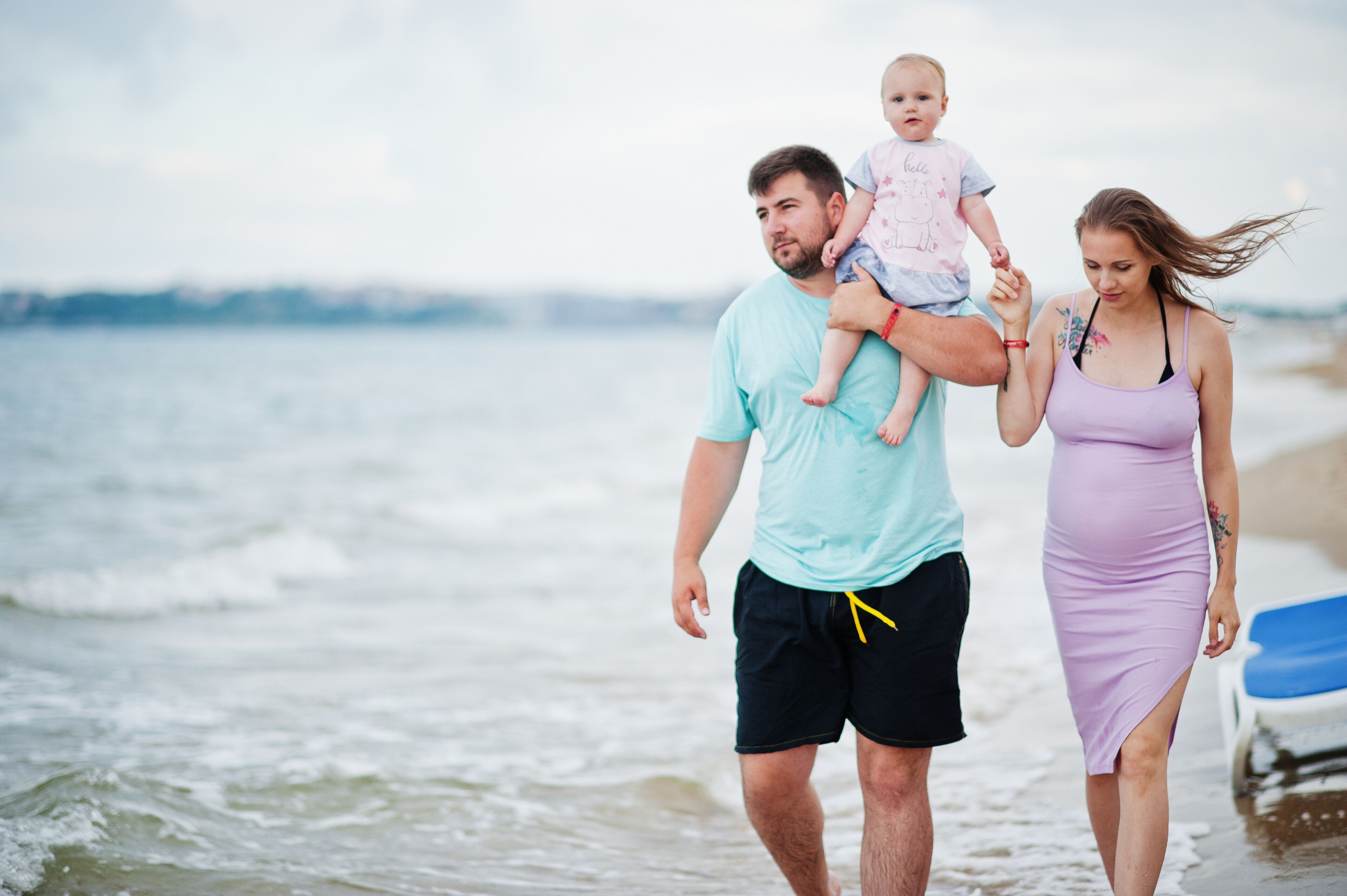Summer vacations. Parents and people outdoor activity with children. Happy family holidays. Father, pregnant mother, baby daughter on sea sand beach.