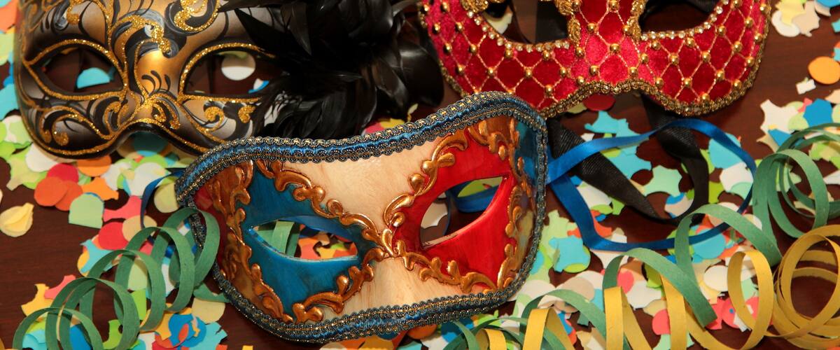 Three ornate masks with gold and red decorations, surrounded by colorful streamers.
