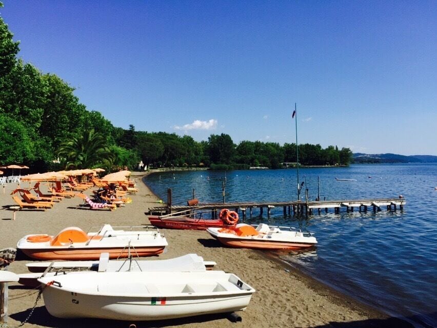 A beach with boats, a dock, and a clear blue sky.