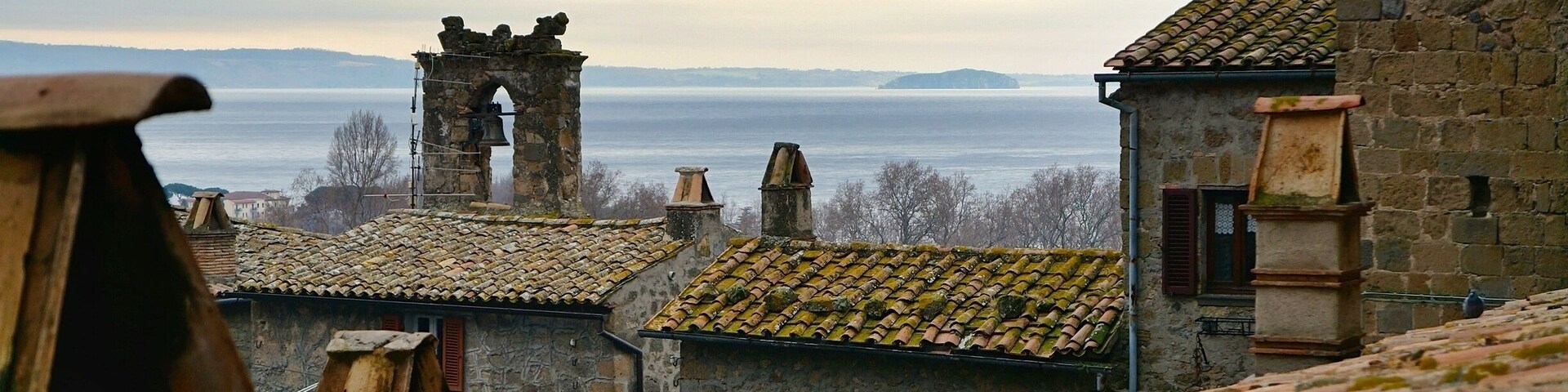 Un pueblo costero con edificios de piedra, una torre de campanas y vistas al mar.