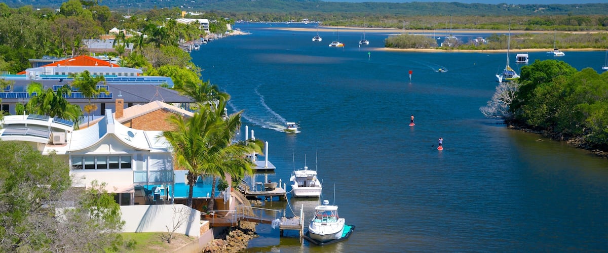 A coastal marina with boats, a beach, and a mountain in the background.