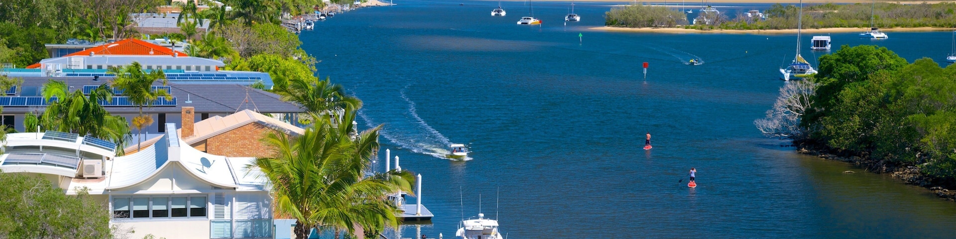 A coastal marina with boats, a beach, and a mountain in the background.