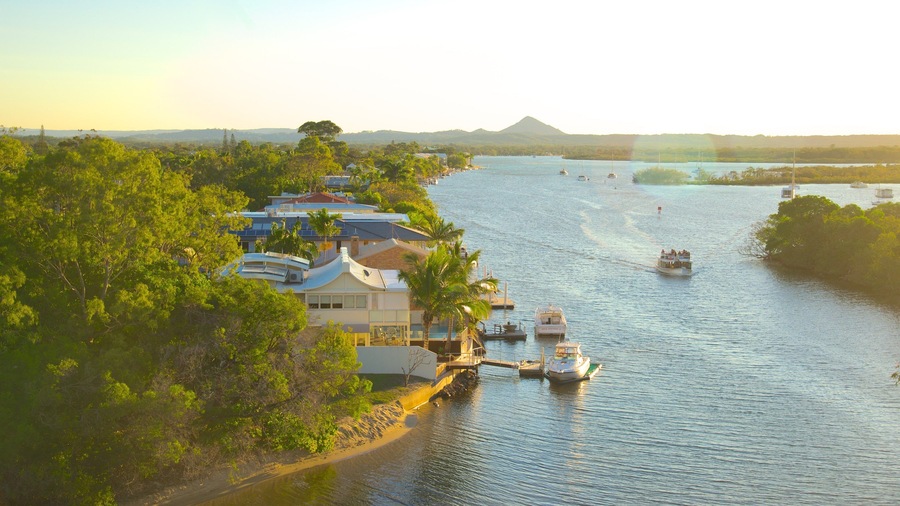A river with boats, a house, and a mountain in the background.