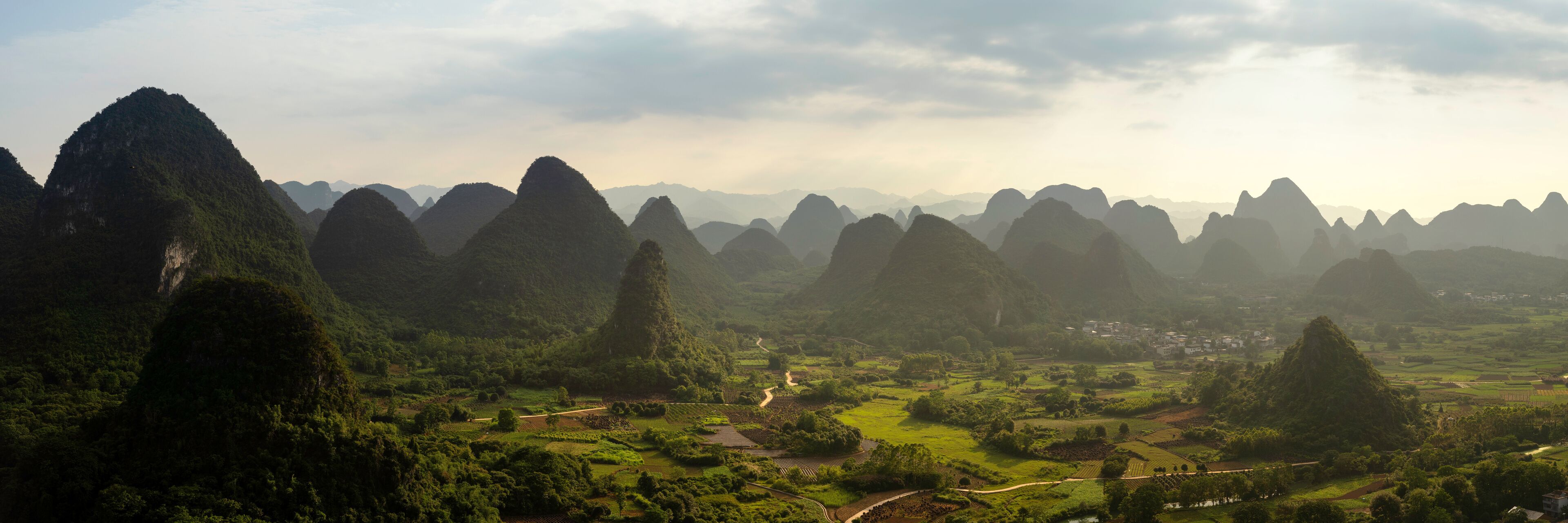A mountainous landscape with terraced fields and a small village.