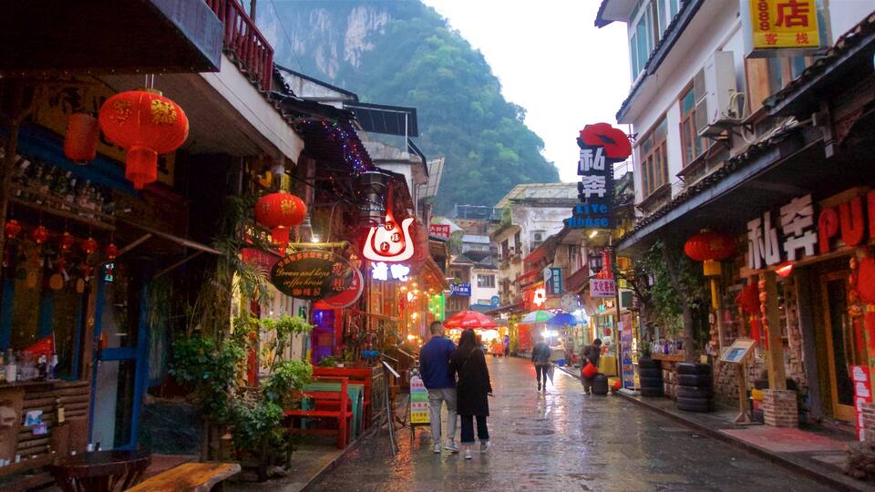 A narrow street with traditional architecture, red lanterns, and signs in a foreign script.