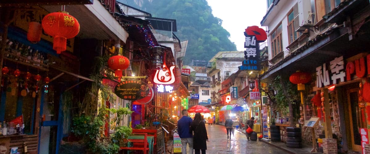 A narrow street with traditional architecture, red lanterns, and signs in a foreign script.