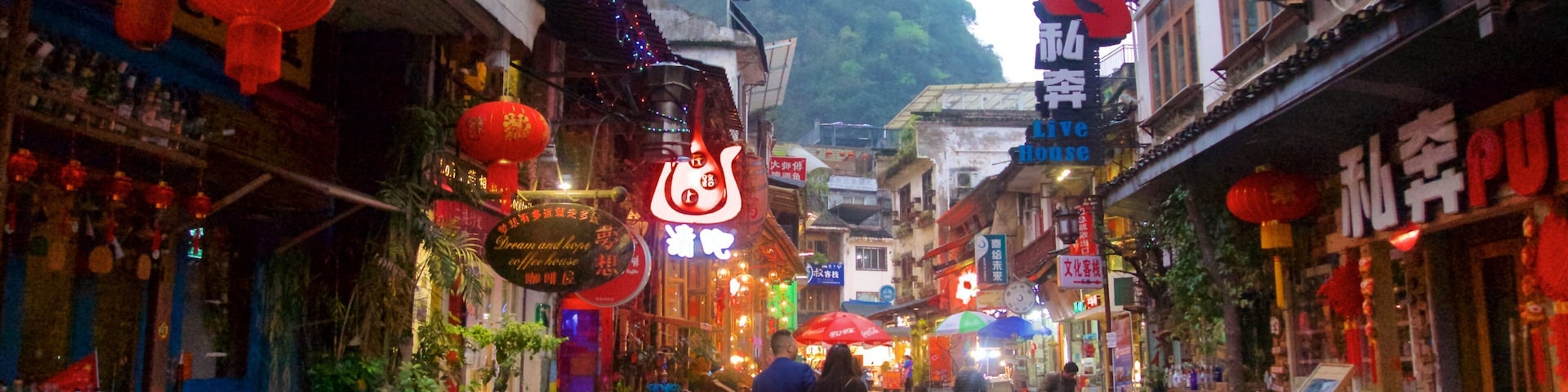 A narrow street with traditional architecture, red lanterns, and signs in a foreign script.