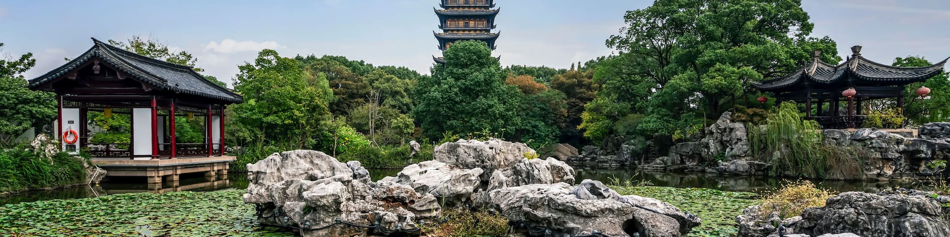 A pagoda, a pavilion, and a pond with rocks and lily pads.