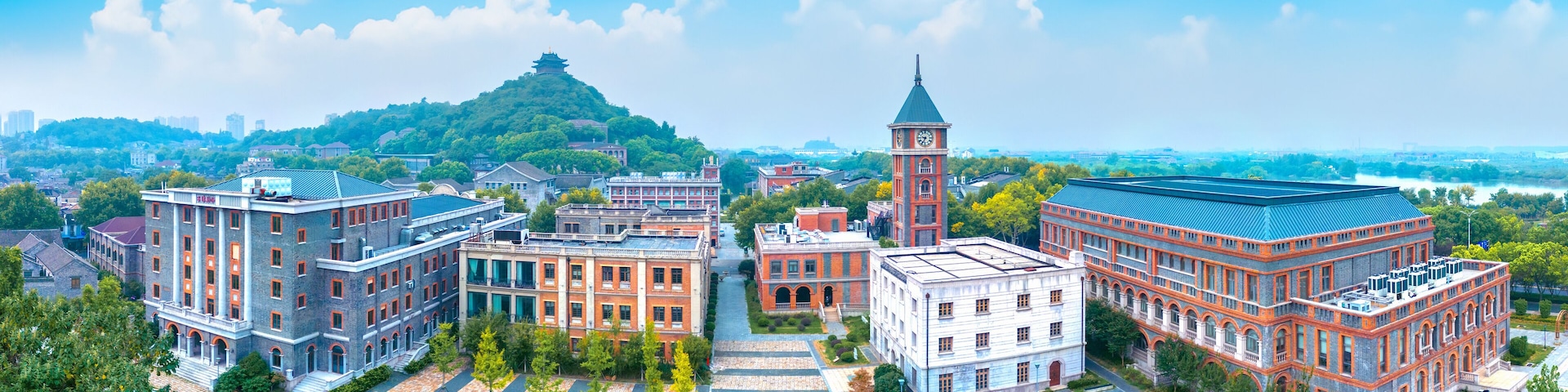 A cityscape with a prominent clock tower, a pagoda on a hill, and various historic buildings.