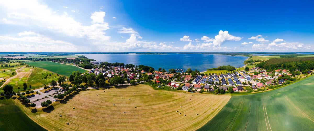 A coastal town with a marina, green fields, and a large body of water.