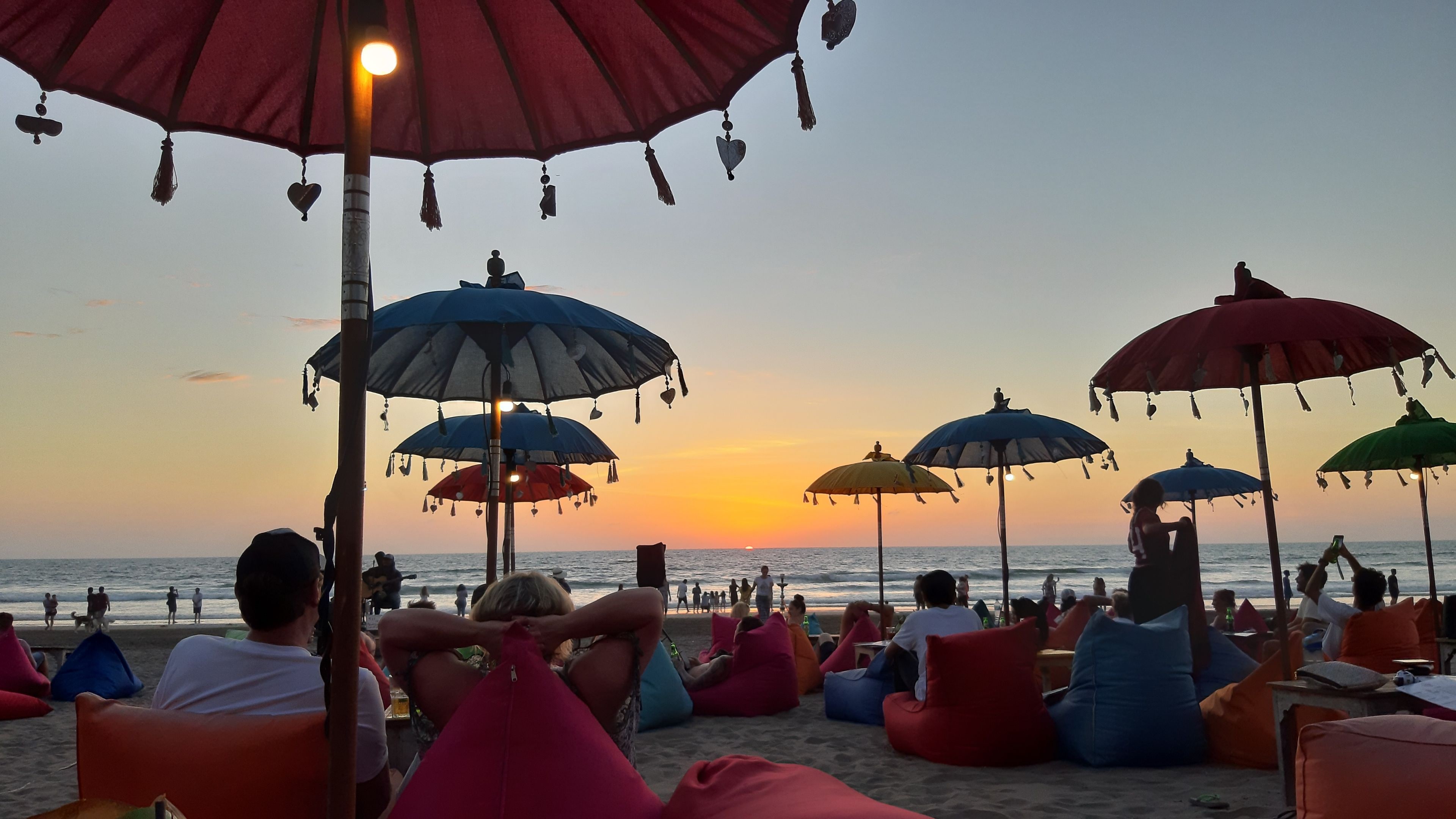 People enjoying the sunset view on double six beach in Bali and sitting on sofa cushions and under Balinese umbrellas, November 8, 2019