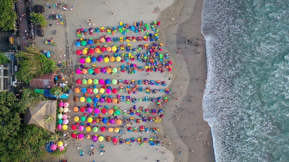 A beach with colorful umbrellas and people.