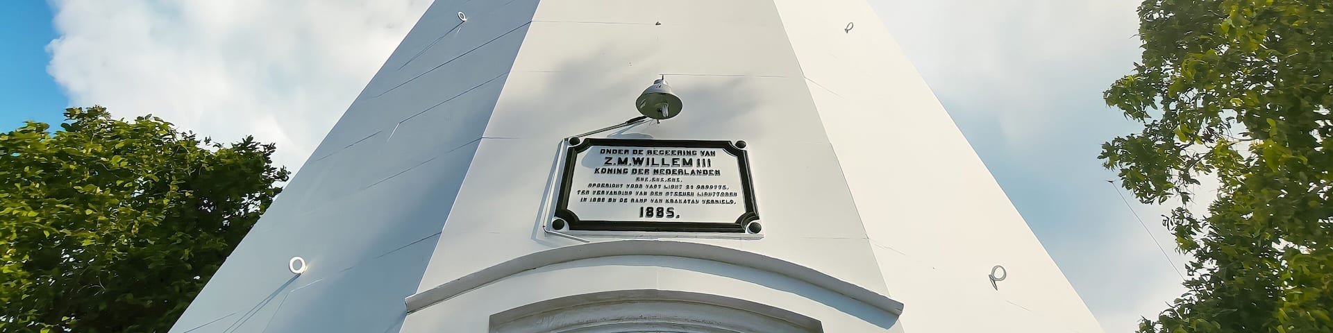Anyer, Indonesia-March 31, 2021: a historic lighthouse building that has a white color with several windows. The sky background is blue and there are colored clouds called the Mercusuar Cikoneng