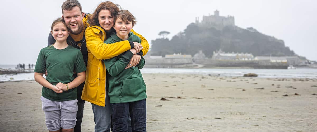 A family on a beach with a castle in the background.