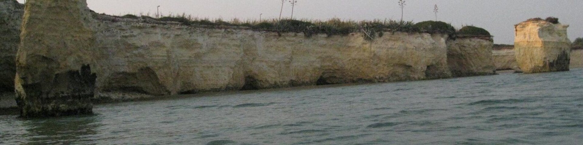 Paisagem costeira com falésias rochosas e mar calmo.