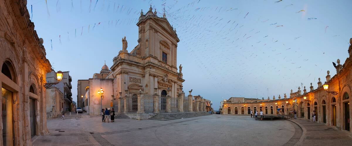 A historic plaza with a prominent church, ornate architecture, and a clear sky.
