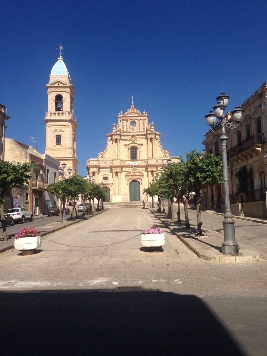 A street leading to a large church with a bell tower and a dome.