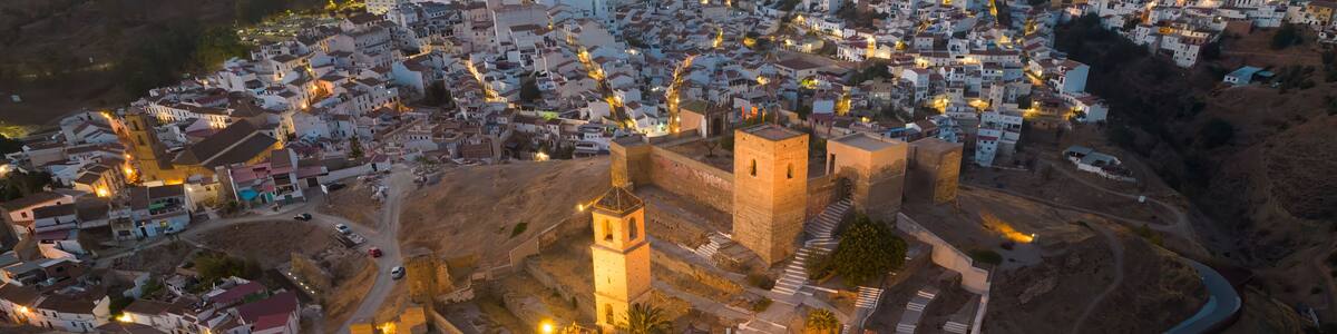 An aerial view of a historic walled town with prominent towers and a central square.