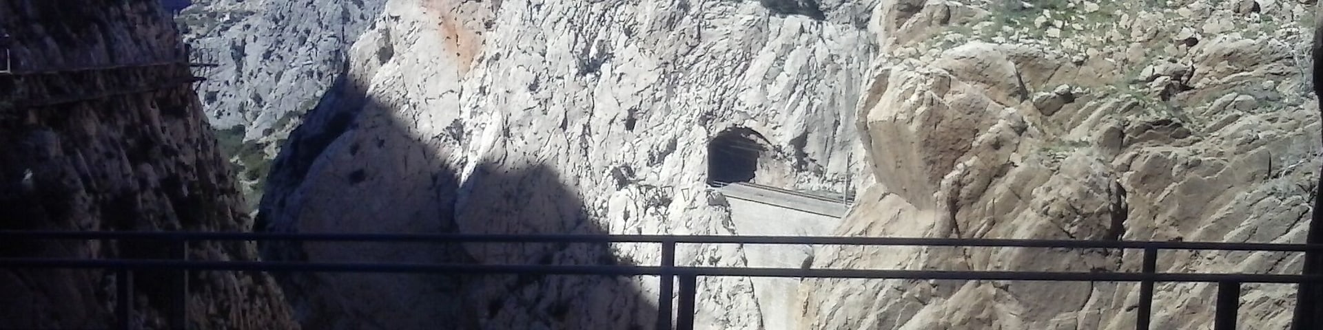 Um penhasco rochoso com uma passagem estreita e uma pequena estrutura semelhante a uma caverna.