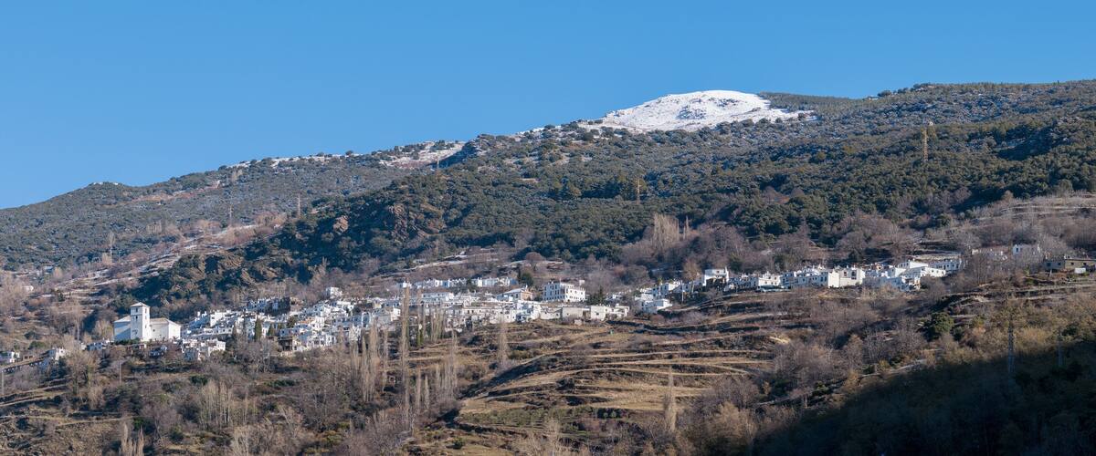 A town nestled in a valley with a snow-capped mountain in the background.
