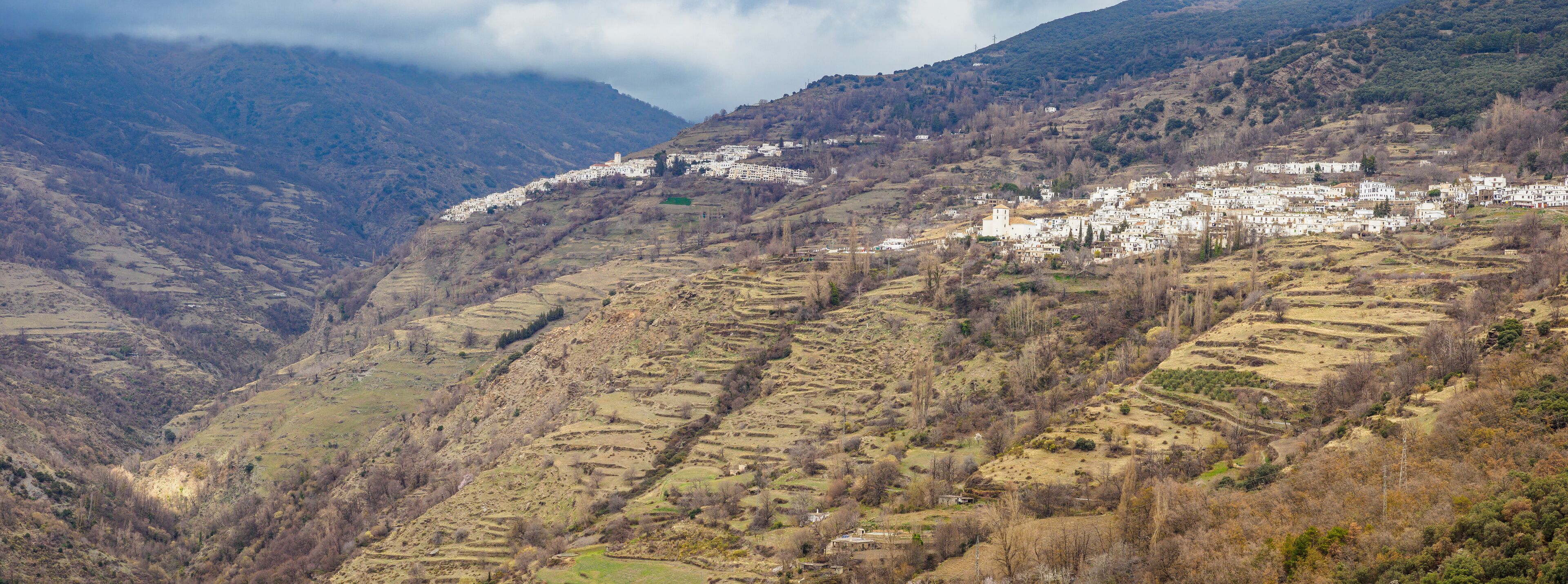 A mountainous village with terraced fields and white buildings.