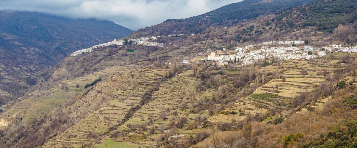 A mountainous village with terraced fields and white buildings.
