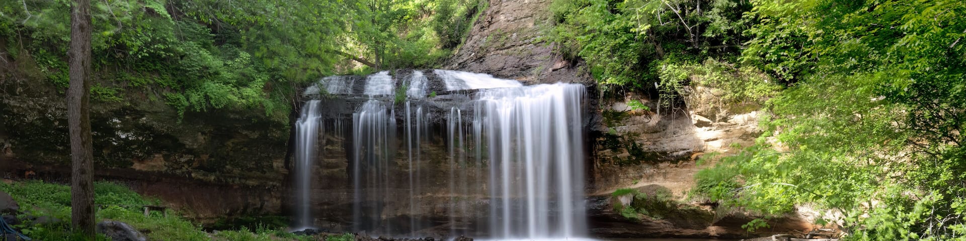 A waterfall in a forested area with a rocky stream below.