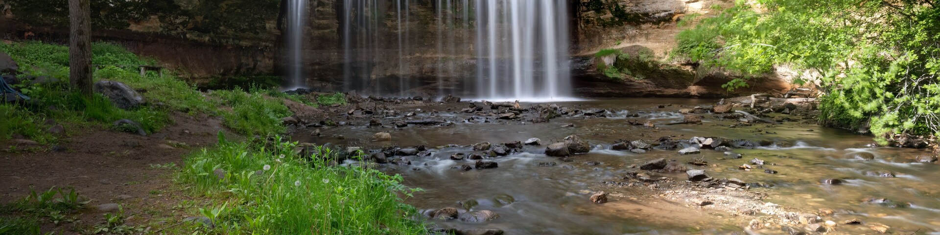 Una cascada en un área boscosa con un arroyo rocoso debajo.