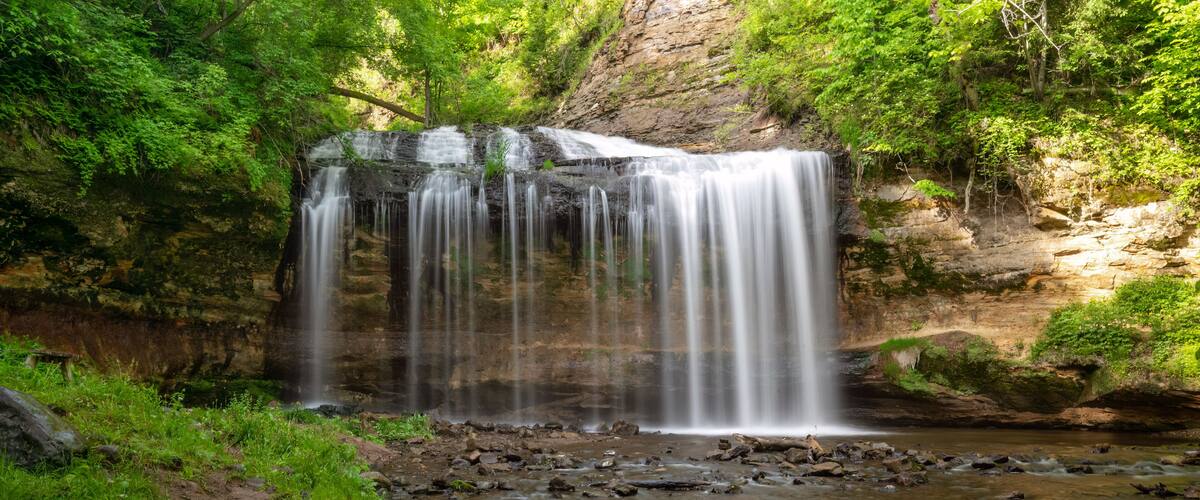 A waterfall cascading over rocks in a forested area.